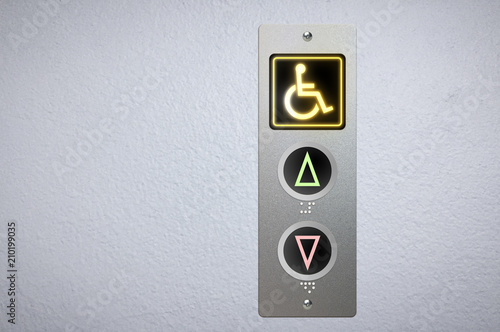 Elevator buttons panel with an amber glowing light button for handicap and Braille code for the visually impaired.