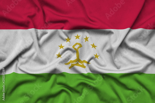 Tajikistan flag  is depicted on a sports cloth fabric with many folds. Sport team banner photo