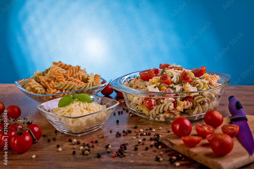 Delicious pasta salad or Mediterranean salad. Tomatoes mozzarella basil corn spice and olive oil on a wooden table. Traditional Italian food Delicious pasta salad or Mediterranean salad. Tomatoes mozzarella basil corn spice and olive oil on a wooden table. Traditional Italian food
