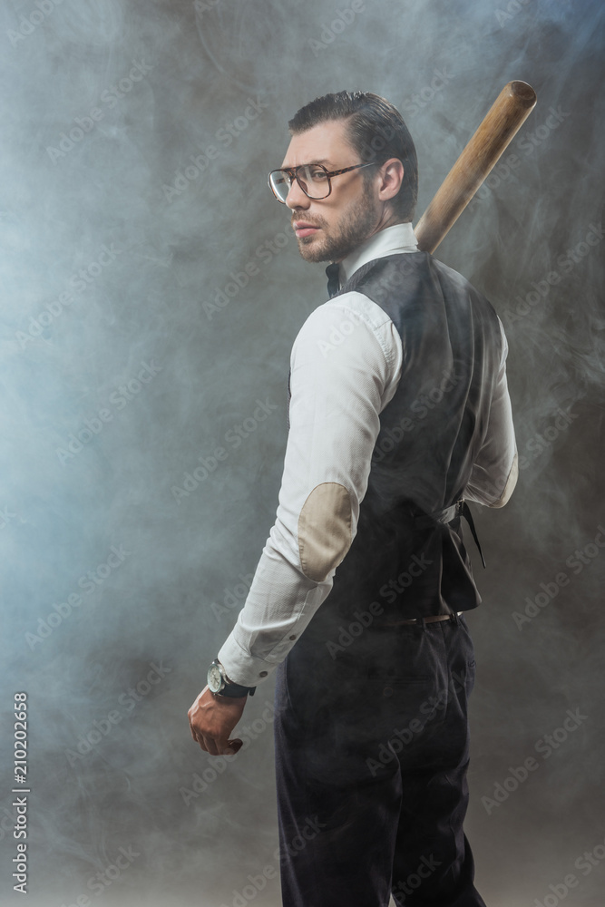 handsome man in bow tie and eyeglasses holding baseball bat and looking away in smoke handsome man in bow tie and eyeglasses holding baseball bat and looking away in smoke