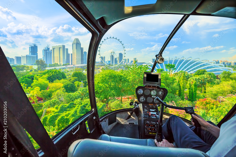 Fototapeta premium Wnętrze kokpitu helikoptera latające na Widok z lotu ptaka na panoramę Singapuru i ogród park nad zatoką Słynna promenada marina bay w Singapurze.