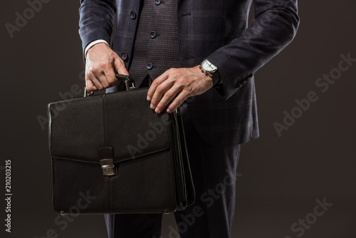 cropped shot of businessman holding briefcase isolated on black