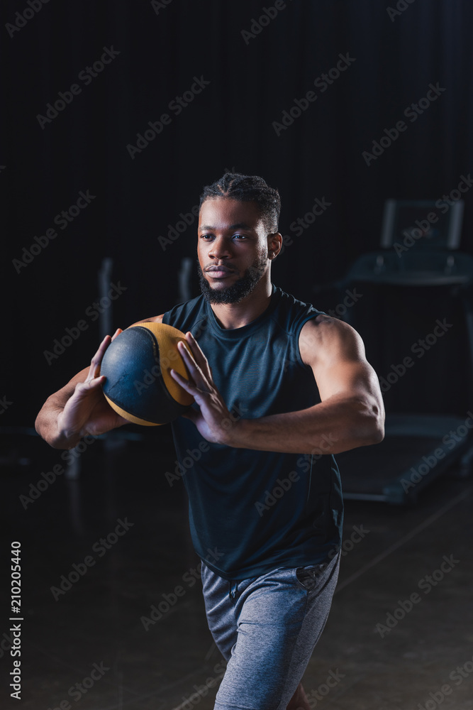 muscular african american sportsman holding ball while exercising in gym muscular african american sportsman holding ball while exercising in gym