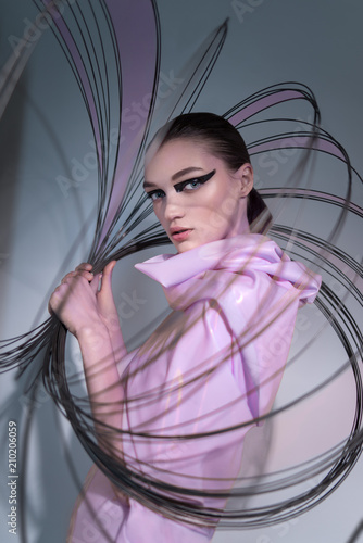 Plakat w ramie Portrait of woman in pink dress posing at camera with thin circles