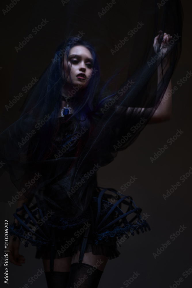 Woman with red hair and black veil posing on dark background