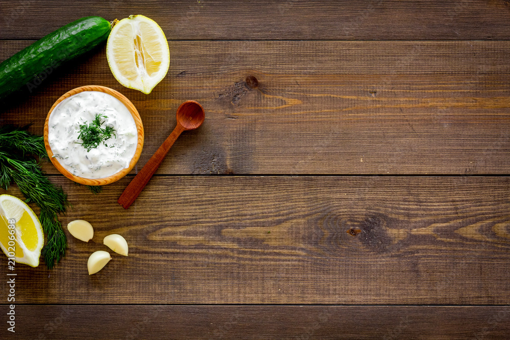 Greek yogurt dip with greenery, cucumber, oranges, garlic on dark wooden background top view space for text Greek yogurt dip with greenery, cucumber, oranges, garlic on dark wooden background top view space for text