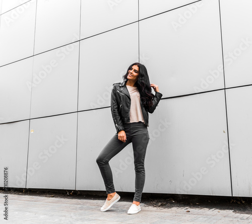 young latin woman walking with happy emotion on grey wall