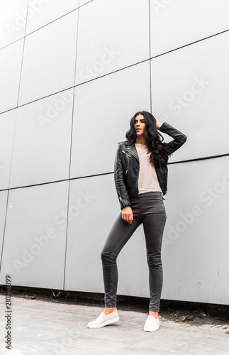 young latin woman walking with happy emotion on grey wall