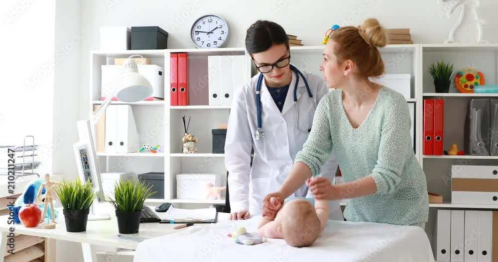 mum doing gymnastics of baby hands lying on table during appointment with doctor. mum doing gymnastics of baby hands lying on table during appointment with doctor.