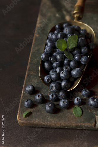 Fresh juicy blueberries on a vintage metal scoop. Close-up, selective focus, low key.