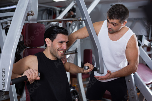 Man during training with instructor in gym
