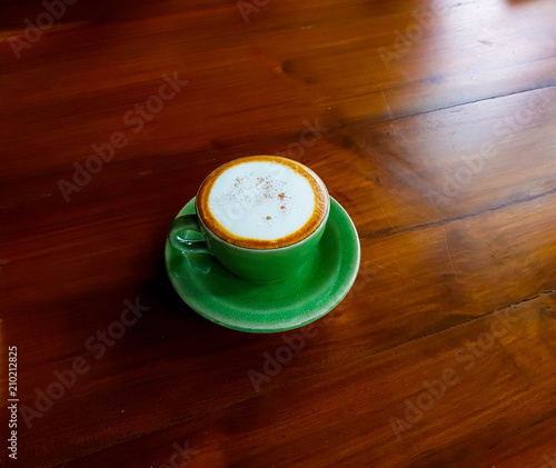 Hot coffee in the green cup on wood table 
