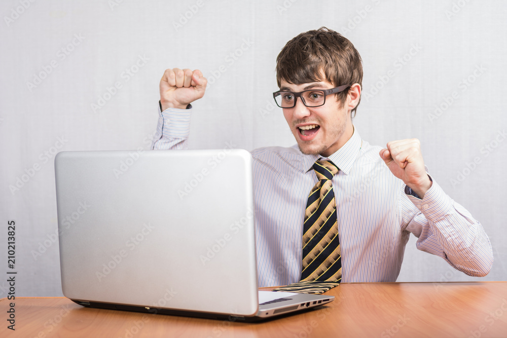 A young Man sitting at a table with a laptop in a shirt and tie A young Man sitting at a table with a laptop in a shirt and tie