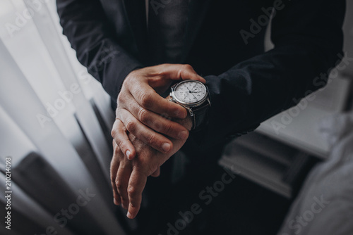 Schilderij op canvas businessman checking time on his wrist watch, man putting clock on hand,groom ge