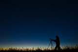 The astronomer photographs the night starry sky on a digital camera using a tripod.