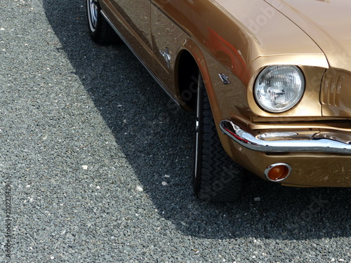 Goldglänzender amerikanischer Sportwagen der Sechzigerjahre im Sommer auf grauem Schotter beim Oldtimertreffen in Lage bei Detmold am Teutoburger Wald in Ostwestfalen-Lippe