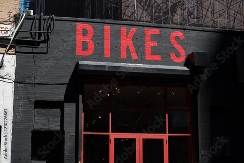 Exterior of a generic bike shop in New York. Bikes painted in red on black brick building. Generic bicycle storefront painted red and black. Facade of a bike store in an urban area, USA.