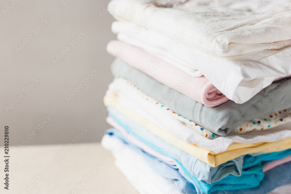 A stack of clean folded cotton clothes ready for ironing. Everyday homework concept. Soft focus. A stack of clean folded cotton clothes ready for ironing. Everyday homework concept. Soft focus.
