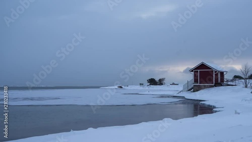 Timelapse of snow falling on sauna near almost frozen lake in Hanko, Finland