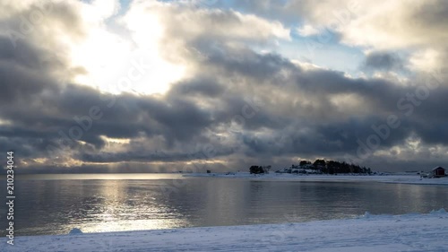 Timelapse of clouds passing over bay and snow covered beach in winter