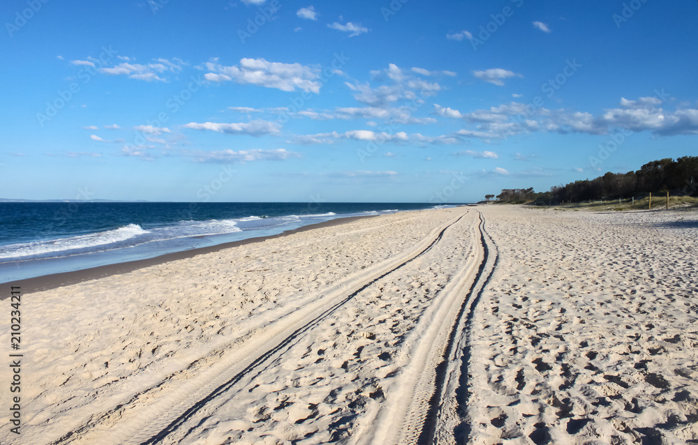 Tracks in the sand - perspective of tire tracks along an empty beach disappearing over the horizon Tracks in the sand - perspective of tire tracks along an empty beach disappearing over the horizon