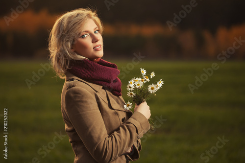 Happy young blond fashion woman wearing classic beige coat walking outdoor