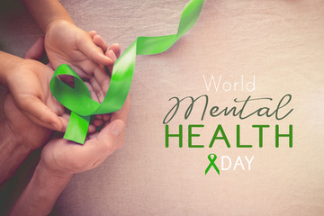 Adult and child hands holding Lime GreenRibbon, world Mental health day