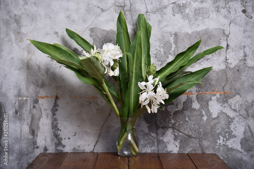 Bouquet of ginger lily in glass vase on gray background