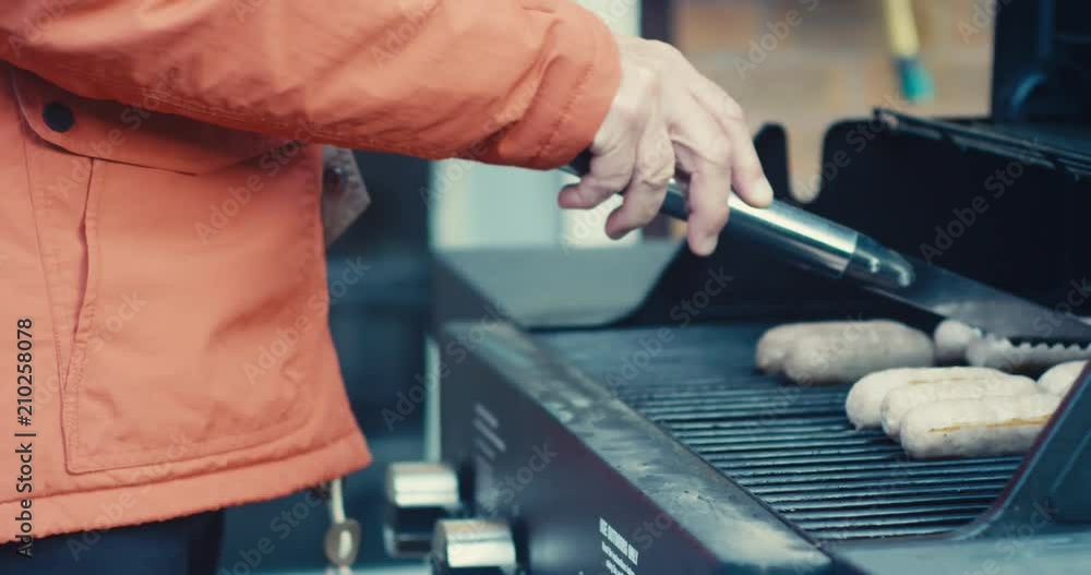 Senior man cooking sausages on barbecue Senior man cooking sausages on barbecue