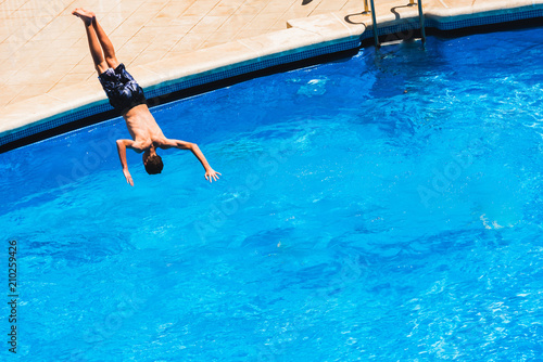 Young men jumping into a pool and splashing