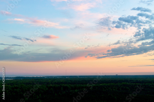 Sunset clouds with forest and pastel colors of shining sun on dramatic sky. Panoramic sunset  amazing view. Copy space