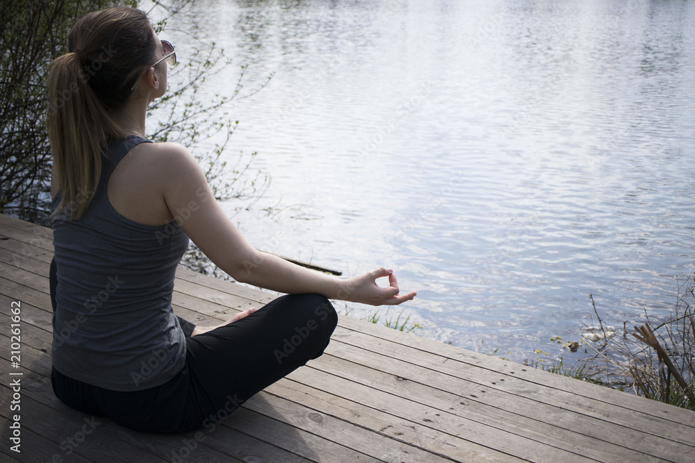 Young girl practices yoga on the shore of the lake, the concept of enjoying privacy and concentration, sunlight Young girl practices yoga on the shore of the lake, the concept of enjoying privacy and concentration, sunlight