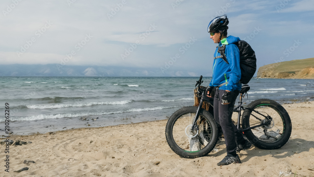 Fototapeta premium Fat bike also called fatbike or fat-tire bike in summer driving on the beach. The guy is going straight on the beach. On the sand on such a bike ride is not difficult.