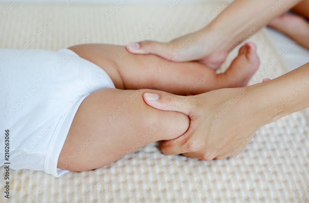 Mother hand massaging to leg of infant baby on the bed at home. Mother hand massaging to leg of infant baby on the bed at home.