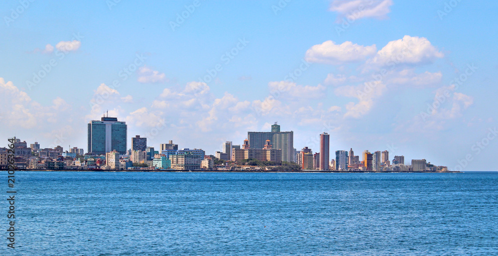 View of the panoramatic Havana in Cuba. There is blue sky and blue ocean and a lot of urbanic buildings. It is situated in carribean in America. 