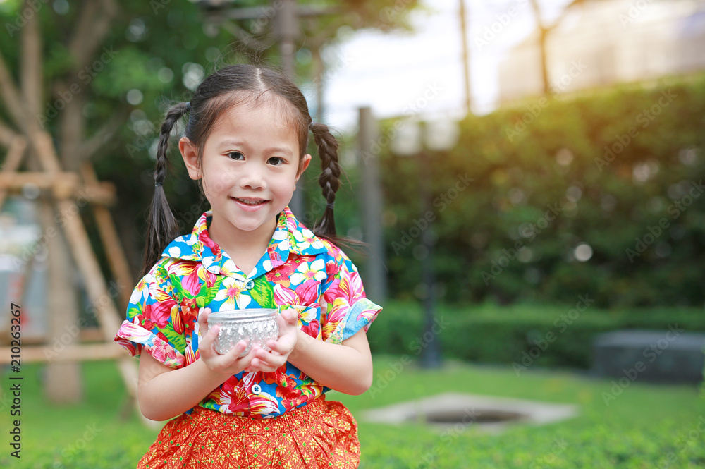 Happy little Asian thai children in thai period dress holding bowl of water to playing in songkran festival (Thai new year - water festival). Happy little Asian thai children in thai period dress holding bowl of water to playing in songkran festival (Thai new year - water festival).