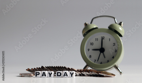 The coins placed in front of the alarm clock and the text 'PAY DAY' photo
