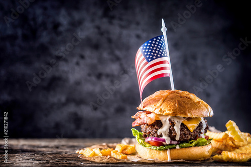 Close-up home made beef burger with american flag and fries on wooden table