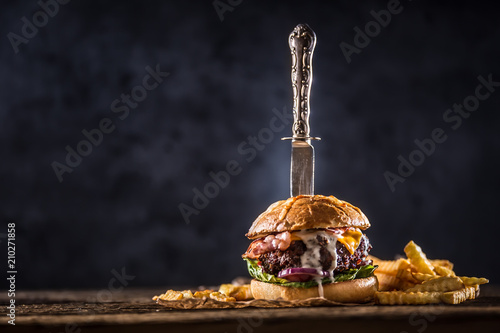 Close-up home made beef burger with knife and fries on wooden table