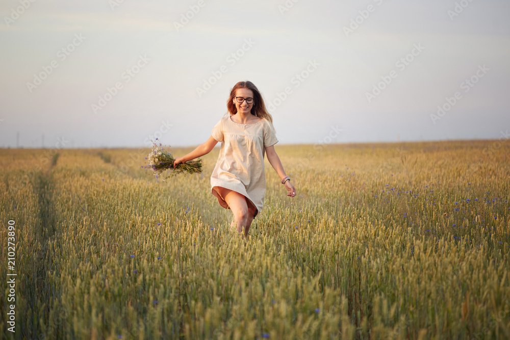 girl with flowers walking on a grain field. girl with flowers walking on a grain field.