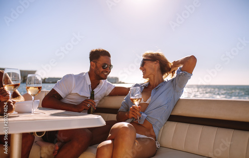 Smiling couple sitting on a boat with drinks © Jacob Lund