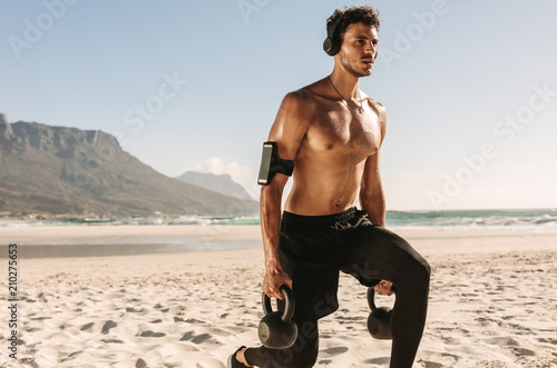 Fototapeta Naklejka Na Ścianę i Meble -  Man doing fitness training at the beach with kettlebells