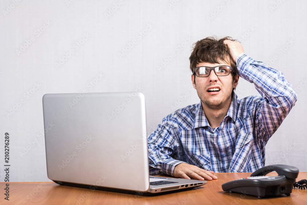young guy with glasses at the Desk upset young guy with glasses at the Desk upset