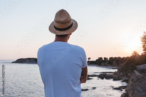 Young man enjoying sunset on a cliff at a seaside