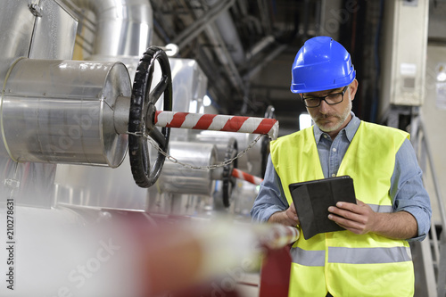 Industrial technician connected with tablet in recyling plant photo