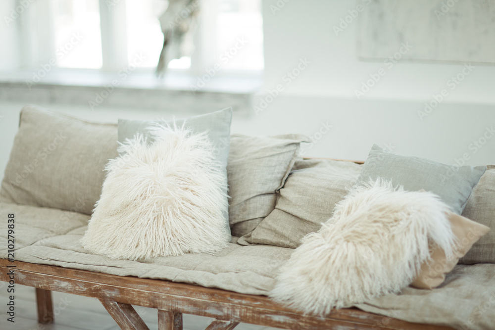 A self-made sofa with light soft pillows in a light-white interior A self-made sofa with light soft pillows in a light-white interior