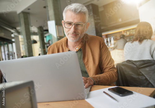 Man in trendy coffee shop working on laptop computer