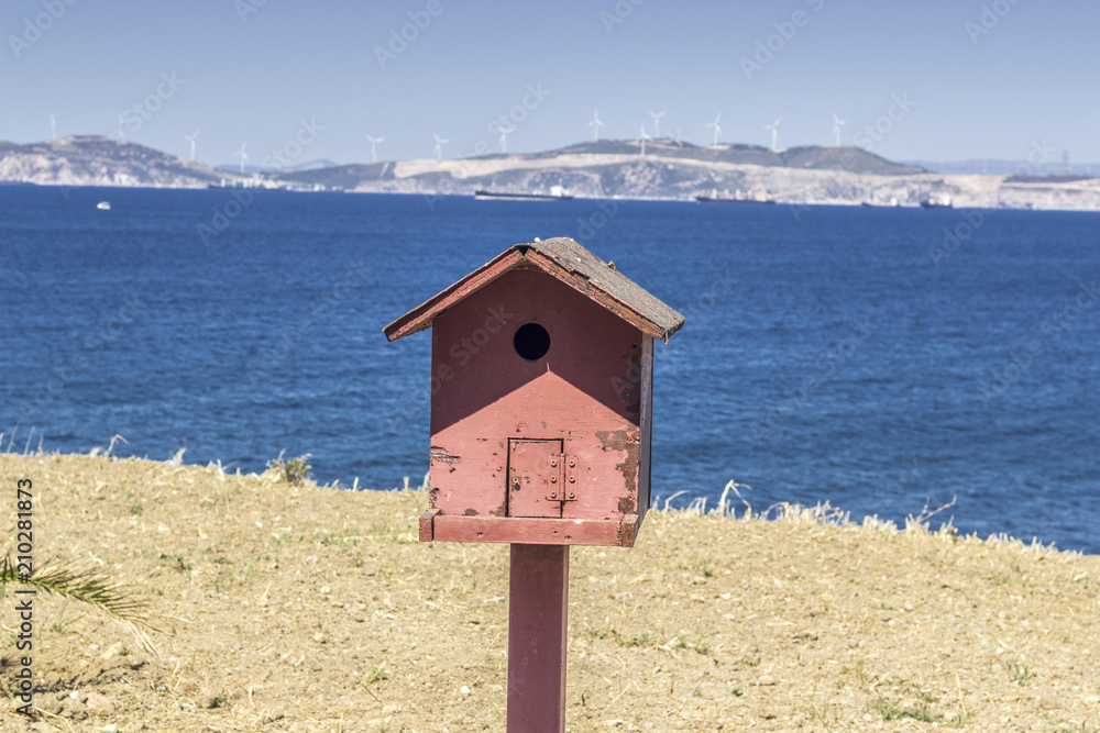 Front close shot of colorful bird house near coastline at summertime