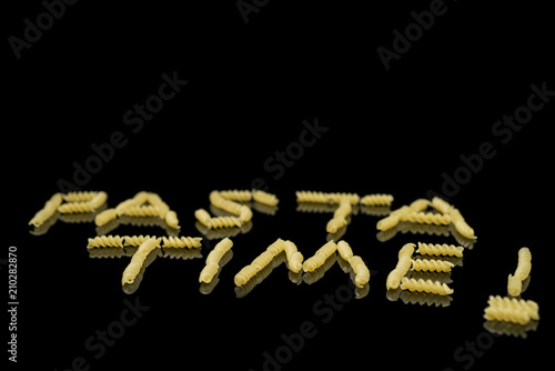 Pasta layed on a black background that spells pasta time © notoriusd