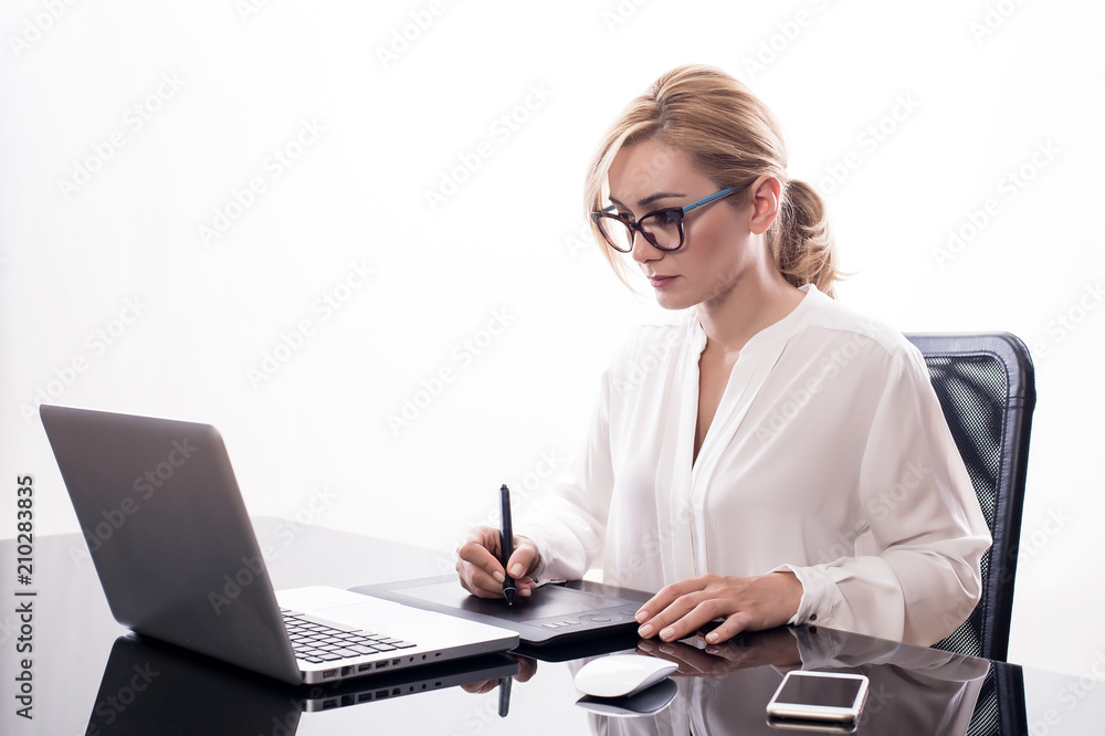 Donna d'affari seduta alla scrivania con tavoletta grafica su fondo bianco Donna d'affari seduta alla scrivania con tavoletta grafica su fondo bianco